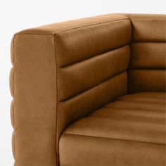 a brown leather couch sitting on top of a white floor