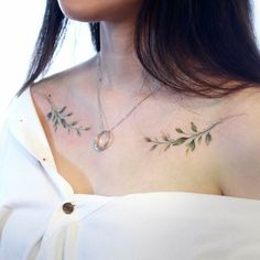 a woman wearing a white dress with green leaves on her chest and an oval necklace