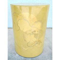 a yellow vase sitting on top of a gray floor next to a white wall with flowers painted on it