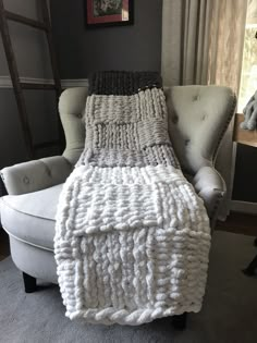 a white chair sitting next to a window with a blanket on it's back