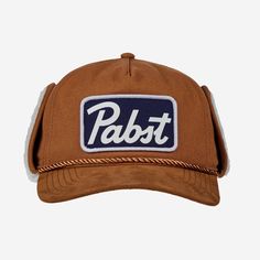 Stay warm in style with the Pabst Blue Ribbon Beer Shearling Hat with Ear Flaps in Tan. The classic Pabst logo adds a fun touch for fans of the iconic brand. This cozy hat features soft shearling lining and ear flaps to keep you snug on chilly days. Perfect for winter outings or casual wear, this hat is both practical and stylish. Shearling Hat, Fun Hats, Hat With Ear Flaps, Pabst Blue Ribbon Beer, Grunge Hippie, Ribbon Logo, Mens Hats Baseball, Brown Hat, Flex Fit Hats