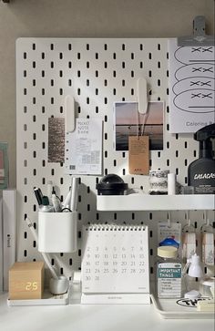 a desk with various items on it and a calendar attached to the wall behind it