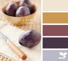 plums in a wooden bowl with a knife on a napkin next to the color scheme