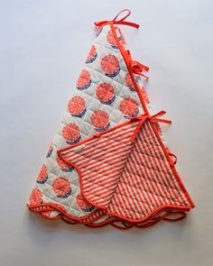 three red and white napkins are stacked on top of each other, one with an orange ribbon