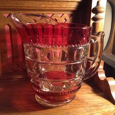 a red glass pitcher sitting on top of a wooden table