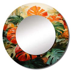 a round mirror with an orange and green leaf pattern on the front, surrounded by tropical leaves