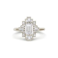 an emerald cut diamond ring with baguetts on the shoulders and side stones set in 18k white gold