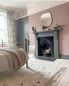 a bedroom with pink walls, white carpet and a fireplace in the corner that has a mirror above it