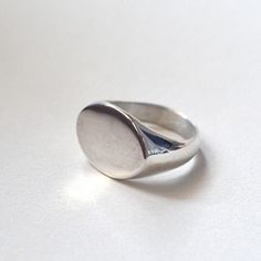 Tabula Rasa. Start your story. A moment of silence before writing, before characters enter, a path is laid. A blank page. The beginning and its freshness. . Kept in the spirit of minimalism and simplicity, a silver signet ring with a streamlined shape and an oval front. The piece is handmade in wax and then cast in sterling silver, hand-finished. . Comfortable. Visible. Ladies'. Men's. Unisex. . The signet ring is polished. Weight of the ring: 10 - 11 g. Size: please choose from the table of ava Modern Oval Sterling Silver Signet Ring, Sterling Silver Polished Signet Ring, Sterling Silver Signet Ring With Polished Finish, Sterling Silver Rounded Signet Ring With Polished Finish, Silver Oval Signet Ring For Everyday, Minimalist Oval Sterling Silver Signet Ring, Minimalist Silver Signet Ring With Polished Finish, Minimalist Sterling Silver Dome Ring, Silver Oval Dome Ring Minimalist Style