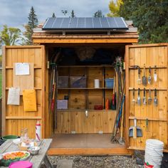 a wooden shed with a solar panel on the roof and lots of utensils in it