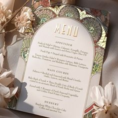 a menu with flowers on the table next to it