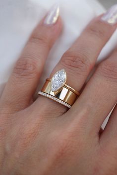 a woman's hand with two gold rings on it and a diamond ring in the middle