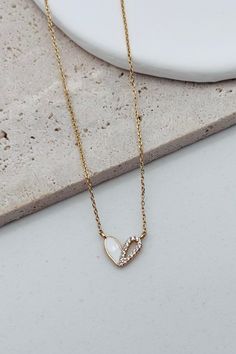 This dainty Tiny Heart Necklace features a delicate gold and white accent adorned with tiny rhinestones. The delicate chain includes an extender for a customizable fit. Elevate any outfit with this elegant and timeless piece. Length: 16" Extender Chain: 2" Finish: Gold Plating Product: Cubic Zirconia White Heart Necklace With Chain, White Charm Necklace With Adjustable Chain For Anniversary, White Charm Necklace With Delicate Chain For Anniversary, White Charm Necklace With Delicate Chain For Valentine's Day, Dainty White Heart Necklace With Delicate Chain, Elegant White Heart Necklace With Chain, White Heart Pendant Necklace With Delicate Chain, White Gold Plated Charm Necklaces With Delicate Chain, White Heart Pendant Charm Necklace With Adjustable Chain