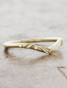 a gold ring with leaves on it sitting on top of a wooden table next to a brick wall