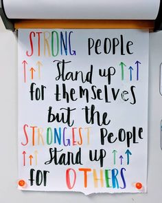 a sign that is hanging on the side of a wall saying strong people stand up for themselves, but the strongest people stand up for others