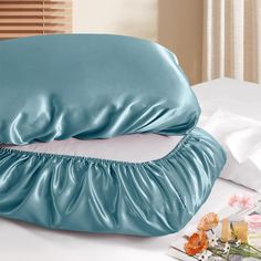 two blue pillows sitting on top of a white bed next to a pillow with ruffled edges