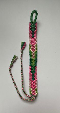 a pink, green and white beaded lanyard with a tassel hanging from it