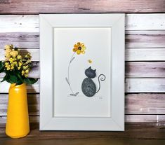 a yellow vase filled with flowers next to a white framed art print on a wooden wall