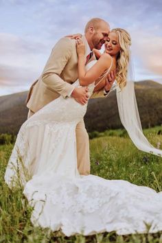 a bride and groom posing for a photo on their wedding day at the top of a mountain