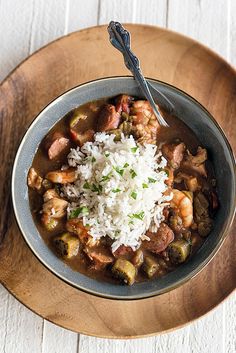 a bowl filled with rice and meat on top of a wooden plate