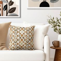 a white couch sitting next to two vases with plants on top of each one