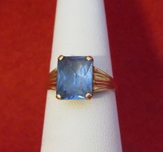 An Original 1960's Swedish 18 Kt Yellow Gold Blue Topaz Ladies Ring - Blue Beauty (Size 6). Visit this shop for a wide variety of Vintage Quality Jewelry, Art, and Collectibles.~Age (approximate): 1960's~Material(s): 18 Karat Yellow Gold~Approx. Size: 6~Approx. Weight: 1.4 dwt~Signature / Brand: Unsigned. ~Condition: Very Good. ~International Shipping: Is Available, please contact us for a quote.~Inventory #: 6129 Formal Blue Sapphire Solitaire Ring, Blue Sapphire Solitaire Ring For Formal Occasions, Emerald Cut Blue Sapphire Ring With 17 Jewels, Classic Blue Emerald-cut Topaz Ring, Blue Vintage Jewelry With Center Stone, Antique Blue Jewelry With Prong Setting, Collectible Blue Sapphire Ring Hallmarked, Collectible Hallmarked Blue Sapphire Ring, Classic Blue Topaz Solitaire Ring