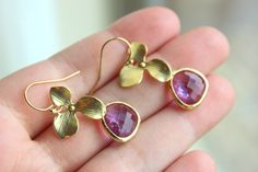 a pair of gold earrings with amethyst flowers