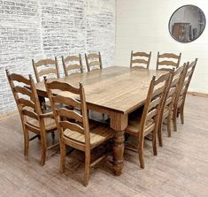 a large wooden table and chairs in a room with brick wall behind it, surrounded by wood flooring