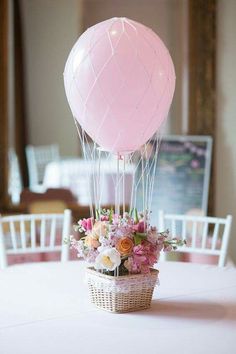 a basket filled with flowers sitting on top of a table next to a pink balloon