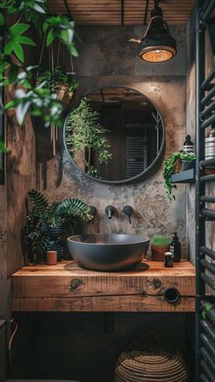 a bathroom sink sitting under a round mirror next to a potted plant on top of a wooden counter