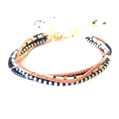 three stranded bracelets with blue and brown beads on a white background, one has a gold plated clasp