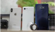 three cell phones sitting on top of a table next to a camera and some other items