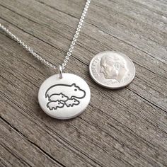 My Mother and Three Baby Hippos Necklace is handcrafted in fine silver and features my original design.  After fabrication, I apply an oxidizing patina and buff it to a soft brushed finish.  The back is stamped with my dragonfly maker's mark and ".999" to signify fine silver. Your choice of sterling silver chain is included. S I Z E : Approx. 11/16" in diameter (17 mm) - about the size of a dime.A V A I L A B I L I T Y : In stock, ships 1-2 days after purchase unless otherwise noted above.Becaus Symbolic Hand Stamped Sterling Silver Necklaces, Symbolic Hand Stamped Sterling Silver Jewelry, Stamped Sterling Silver Necklaces, Stamped Silver Sterling Necklace, Sterling Silver Stamped Necklaces, Silver Stamped Necklaces As Gift For Mom, Hand Stamped Silver Pendant Jewelry, Silver Hand Stamped Necklace For Mom, Symbolic Silver Necklace With Stamped Detail