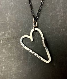 "This sweet-but-not-too-sweet heart necklace is all sterling silver. The pendant is made from stock materials: 12g. round wire for the heart, 20g. rivets, 18g. wrapped wire, 16g. Soldered jump rings connect the pendant to the 18\" long, rolo chain. Handmade T-bar clasp. The back of the pendant has been stamped: stelzer, sterling, handwrought, shown in last pic. The heart is about 1-5/8\" long and 1-2/16\" wide." Heart-shaped Sterling Silver Soldered Necklace, Sterling Silver Heart-shaped Soldered Necklaces, Sterling Silver Heart-shaped Soldered Necklace, Sterling Silver Heart Necklace With Soldered Details, Silver Heart Necklace, Hand Forged, Hand Forged Silver Heart Necklace, Silver Hand Forged Heart Necklace, Sterling Silver Heart Necklace Wire Wrapped, Small Heart Pendant