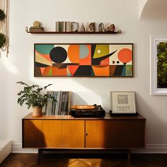 an old record player sits on top of a wooden cabinet in front of a painting