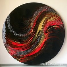 a black plate with red, yellow and silver swirls painted on the inside of it