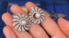 These awesome circa 1950s pierced earrings are each accented with one (1), post set, cultured saltwater Akoya pearl and thirty-nine (39), prong/bead set, old European/brilliant/single cut diamonds. The earrings measure 29.6mm X 25.7mm. The earrings are finished with hinged backs. Fine Jewelry Diamond Pearl Earrings For Evening, Fine Diamond Pearl Earrings For Evening, White Gold Pearl Earrings With 17 Jewels For Wedding, Vintage White Diamond Earrings For Formal Occasions, Fine Jewelry Clip-on Diamond Earrings For Evening, Vintage Round Pearl Earrings For Anniversary, Evening Clip-on Diamond Earrings Fine Jewelry, Classic Akoya Pearl Earrings For Evening, Exquisite Evening Earrings With 17 Jewels