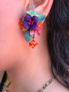 Gorgeous little petunia earring with a central purple polymer clay flower mixed with a striking color combo of red, orange, green and yellow. These earrings are hand sewn together with glass beads and hand painted resin flowers, finished off with a pretty handbeaded bauble. This is a quality piece of jewelry that will last a life time. Created by designer Colleen Toland who has been creating her unique style of vintage jewelry for more than 30 years. All of our pieces come with an engraved tag w Whimsical Multicolor Flower Shaped Jewelry, Multicolor Flower-shaped Jewelry With 3d Flowers, Multicolor 3d Flower Shaped Jewelry, Whimsical Multicolor Flower Jewelry, Adjustable Multicolor Earrings With Flower Charm, Adjustable Multicolor Flower Charm Earrings, Whimsical Multicolor Flower Charm Earrings, Handmade Colorful Flower Earrings, Whimsical Multicolor Flower-shaped Earrings