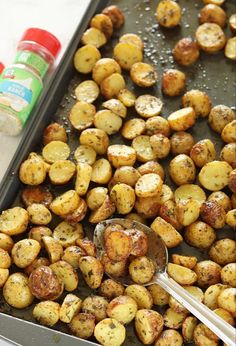 a pan filled with cooked potatoes next to a bottle of ketchup and a spoon