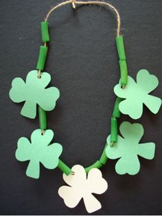 a green and white necklace with four leaf clovers hanging from it's sides