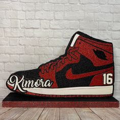 a pair of red and black sneakers sitting on top of a wooden table next to a white brick wall