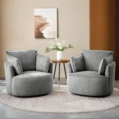 two gray chairs sitting on top of a rug in front of a vase with flowers