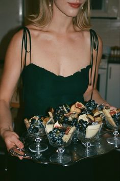 a woman holding a tray with desserts on it