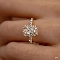 a woman's hand holding an engagement ring with a diamond in the center and two rows of diamonds on each band