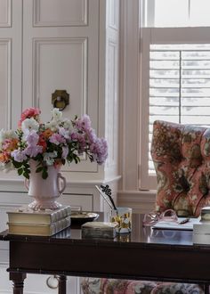 a vase with flowers on top of a table in front of a couch and window