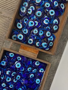 two boxes filled with blue glass eyeballs on top of a floor next to each other