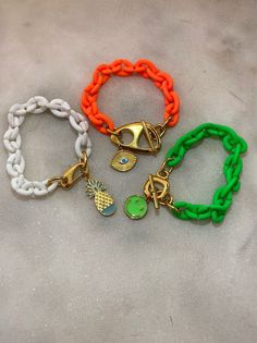 Three different handmade bracelets in similar summer philosophy with acrylic chains and different central charms as pendants. An Evil Eye charm at orange chain, a smile charm at green bracelet, and finaly a pineapple ath the white bracelet. You can choose between 3 different colors with their unique central charms. Wear them all together or separetely as well. In Christina Christi Jewels store you can see more than 35 designs in Women's Bracelets. You can have them in 2-4 Days with DHL EXPRESS S Trendy Adjustable Chain Bracelet For Beach, Adjustable Chain Bracelets For Beach, Handmade Plastic Jewelry For The Beach, Trendy Green Chain Bracelet As Gift, Trendy Green Chain Bracelet For Gift, White Plastic Jewelry For Beach, Trendy White Bracelets With Lobster Clasp, Adjustable White Chain Bracelet With Lobster Clasp, Trendy White Bracelets With Charms