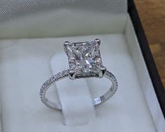 a princess cut diamond engagement ring in a box with diamonds on the sides and inside