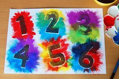 an art project with numbers painted on paper and paintbrushes next to it,