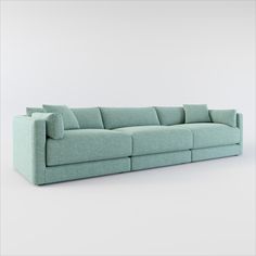 a blue couch with pillows on it in front of a white wall and grey floor